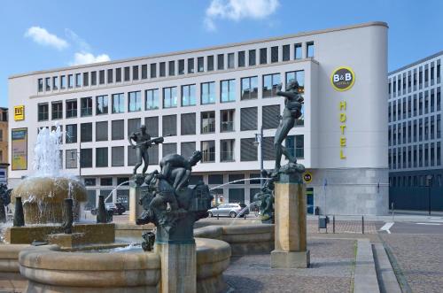 uma fonte com duas estátuas em frente a um edifício em B&B Hotel Halle (Saale) em Halle an der Saale