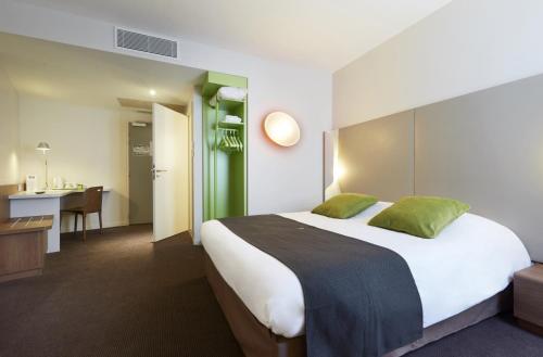 una camera d'albergo con un grande letto e una scrivania di Campanile Annemasse Gare– Genève ad Annemasse