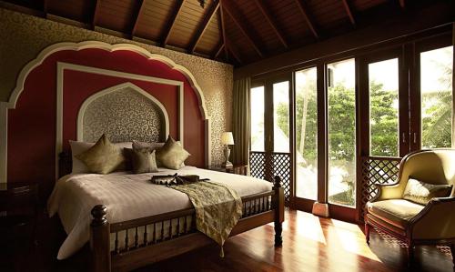 a bedroom with a bed and a chair and windows at Pawanthorn Samui - SHA Plus in Chaweng