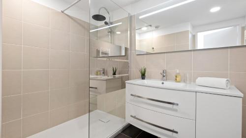 a white bathroom with a sink and a shower at Cannes Marina Appart Hotel Mandelieu in Mandelieu-La Napoule