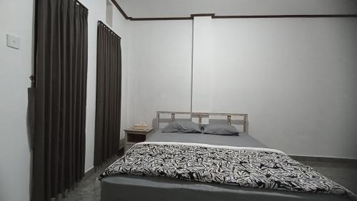una camera da letto con un letto con un piumone bianco e nero di Gending Sari House ad Ubud