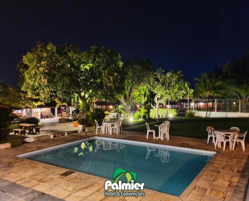 una piscina por la noche con mesas y sillas en Palmier Hotel & Convenções, en Itaboraí