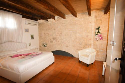 a bedroom with a white bed and a chair at B&B Palazzo Scaraggi Il Solito Posto in Bitonto
