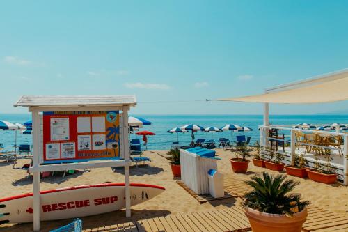 Hotel Saline في بالينورو: وجود علامة على الشاطئ مع لوح ركوب الأمواج على الرمال
