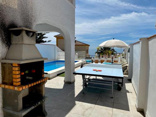 a ping pong table on a patio next to a pool at Nerja Paradise Rentals - Villa Dos Ardillas in Nerja