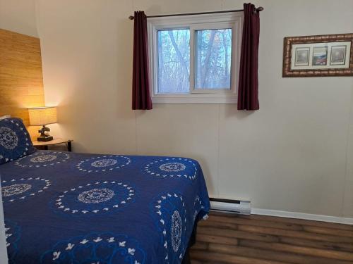 a bedroom with a blue bed and a window at Three Island Motel in Bobcaygeon