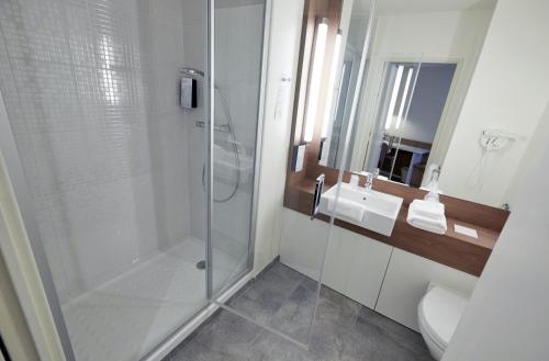 uma casa de banho com um chuveiro e um lavatório. em Campanile Annemasse Gare– Genève em Annemasse