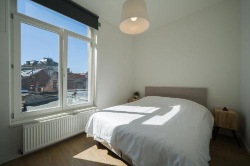 a bedroom with a bed and a large window at Julie's Boutique Guesthouse Ghent in Ghent