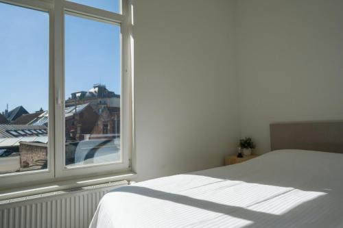 a bedroom with a white bed and a window at Julie's Boutique Guesthouse Ghent in Ghent