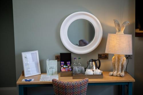 a desk with a lamp and a mirror on a wall at Victoria Hotel by Chef & Brewer Collection in Menai Bridge