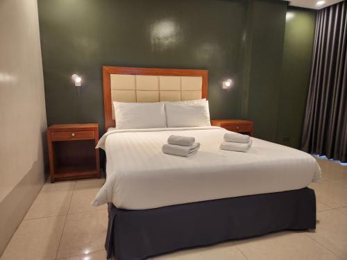 a bedroom with a large bed with two towels on it at Hotel Herencia 625 in Daraga