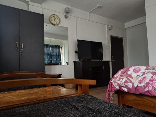 een woonkamer met een bed en een televisie bij Vamoose Mountain Mist in Tawang