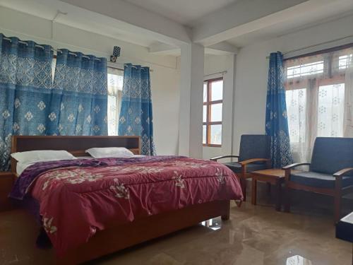 een slaapkamer met een bed, een stoel en ramen bij Vamoose Mountain Mist in Tawang