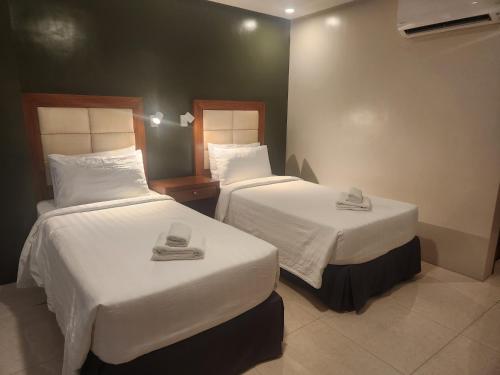 a hotel room with two beds with white sheets at Hotel Herencia 625 in Daraga