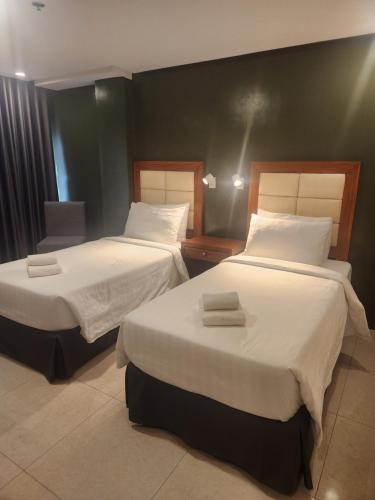 two beds in a hotel room with two bedsvisor at Hotel Herencia 625 in Daraga