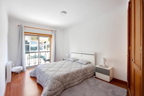 a white bedroom with a bed and a balcony at Corrente do Oudinot perto da praia in Gafanha da Nazaré