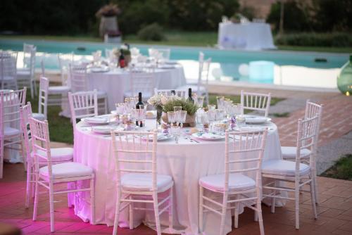 una mesa con mesas y sillas rosas y blancas en Casa Burraia, en Abbadia di Montepulciano