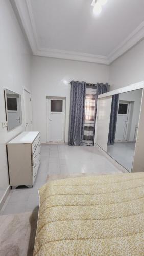 a large white room with a bed and a mirror at F2 Appart Les Ambassades Point E, Dakar in Dakar