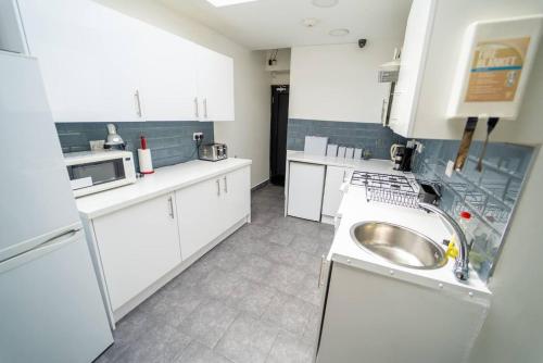 a kitchen with white cabinets and a sink at Modern Studio next to University of Birmingham in Birmingham