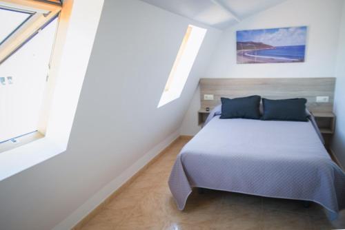 a bedroom with a bed and a large window at Apartamentos pilucha in Muxia