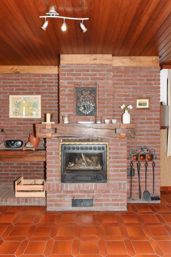 a brick fireplace in a room with a brick floor at Ferienhaeuser Strandburgen in Bensersiel