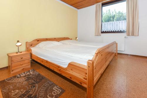 a bedroom with a wooden bed and a window at Ferienhaeuser Strandburgen in Bensersiel