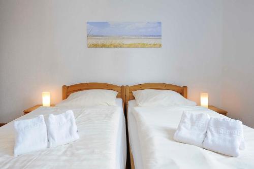 two beds in a room with white sheets and pillows at Ferienhaeuser Strandburgen in Bensersiel
