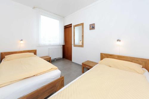 a bedroom with two beds and a window at Ferienhaeuser Strandburgen in Bensersiel