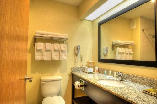 Quality Inn Cherokee في شيرروكي: حمام مع مرحاض ومغسلة ومرآة