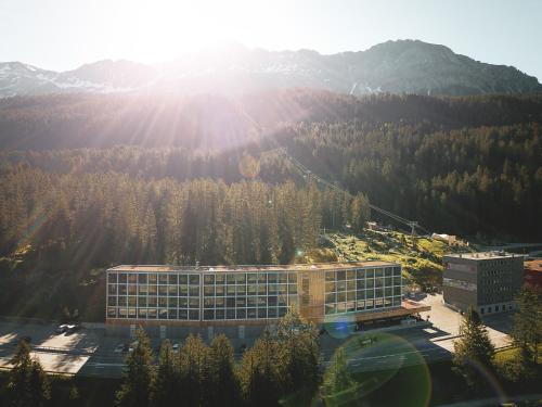 a building in front of a mountain with trees at Revier Mountain Lodge Lenzerheide in Lenzerheide