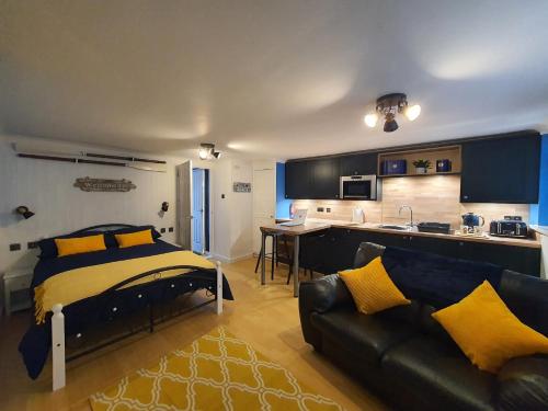 a bedroom with a bed and a couch and a kitchen at Hayling Hideaway, private cosy annex near to beach in South Hayling
