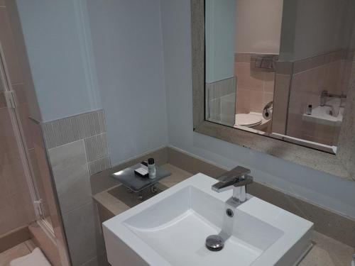 W łazience znajduje się biała umywalka i lustro. w obiekcie Golden Horse Hotel 