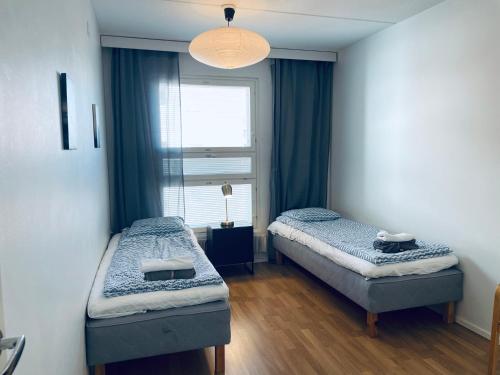 2 camas en una habitación con ventana en Kalastajankuja Apartment, en Espoo