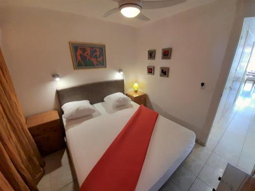 - une chambre dotée d'un lit avec une couverture rouge et blanche dans l'établissement Appartement Village Naturiste Poeme, au Cap d'Agde