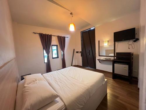 een slaapkamer met een wit bed en een televisie bij The Green Season Resort in Ban Mae Kham Lang Wat