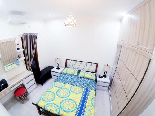 a bedroom with a bed with blue and yellow pillows at Rumah Bungur, Purwomartani in Kalasan