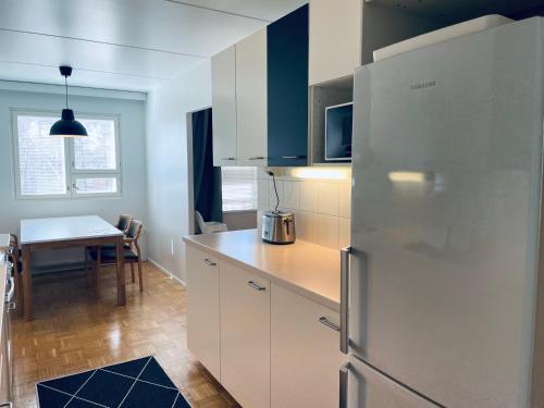a kitchen with a stainless steel refrigerator and a table at Kalastajankuja Apartment in Espoo