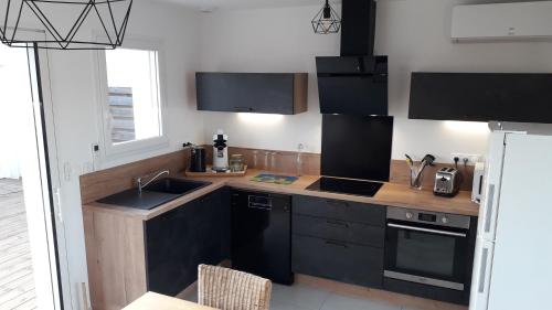 - une cuisine avec des placards noirs et un évier dans l'établissement LOCABEACH, à Longeville-sur-Mer