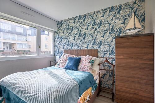 um quarto com uma cama e uma parede coberta de papel de parede em Overlord - Appt 300m plage em Courseulles-sur-Mer