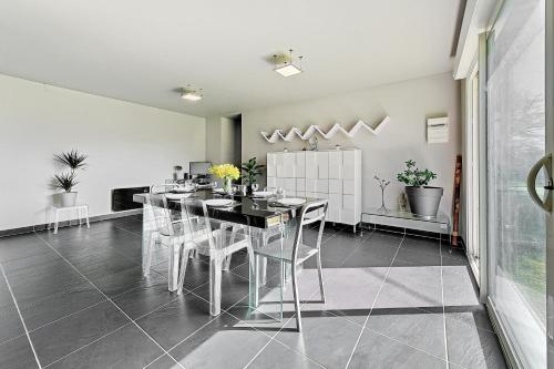 une salle à manger avec une table noire et des chaises blanches dans l'établissement La Coquelière - Belle maison pour 5, à Putanges