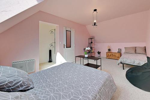 ein Schlafzimmer mit rosa Wänden, einem Bett und einem Sofa in der Unterkunft La Coquelière - Belle maison pour 5 in Putanges