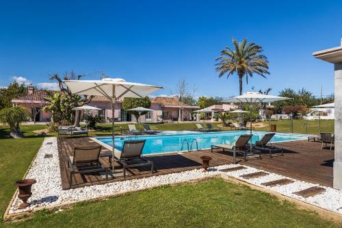 a swimming pool with chairs and umbrellas in a yard at Quinta de Santa Margarida - Charm Country House in Tavira