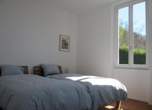 2 Betten in einem weißen Zimmer mit Fenster in der Unterkunft Ca' Dogana Vegia in Pugerna