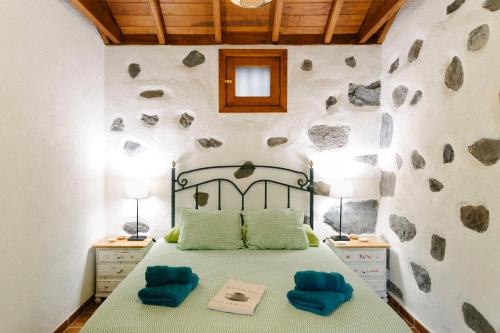 a bedroom with a bed with two blue pillows at Casa Rural Los Chicos Hermigua in Hermigua