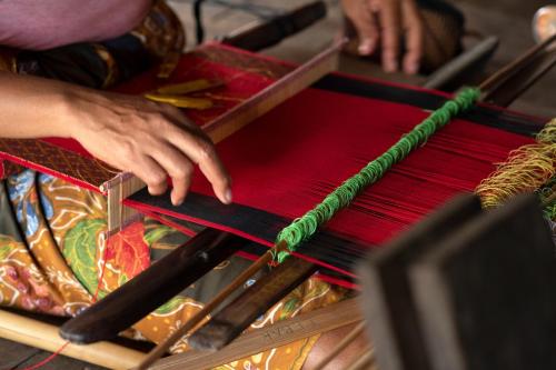 a person is weaving a piece of red thread at The Kayana Beach Lombok in Senggigi 