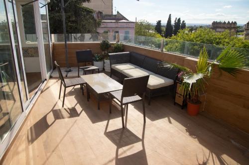 a patio with a couch and chairs on a balcony at Puerta Palma con vistas únicas y aparcamiento in Badajoz