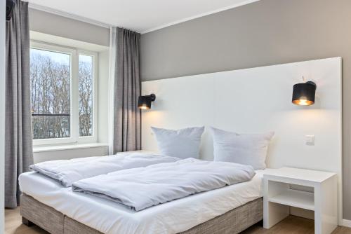 een witte slaapkamer met een groot bed en een raam bij Strandresidenzen Strandresidenzen Haus Dänholm 3 5 in Binz