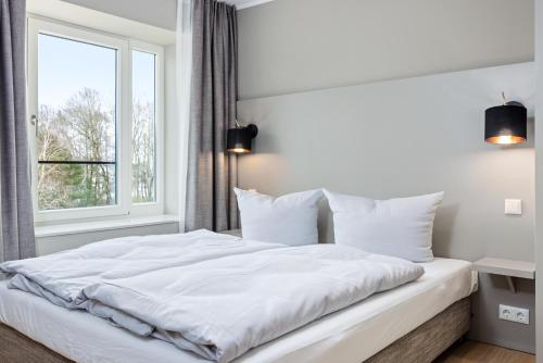 białe łóżko w sypialni z oknem w obiekcie Strandresidenzen Strandresidenzen Haus Dänholm 3 3 w mieście Binz