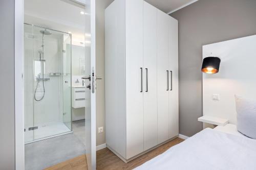 biała sypialnia z prysznicem i łóżkiem w obiekcie Strandresidenzen Strandresidenzen Haus Dänholm 3 3 w mieście Binz