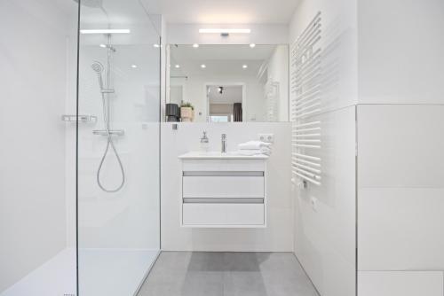 een witte badkamer met een douche en een wastafel bij Strandresidenzen Strandresidenzen Haus Dänholm 3 4 in Binz